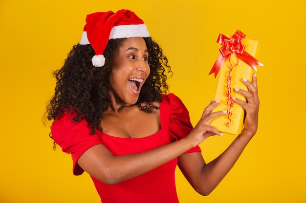 Jovem garota afro segurando um expressivo presente de Natal.