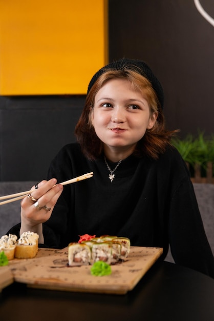 jovem garota asiática come sushi