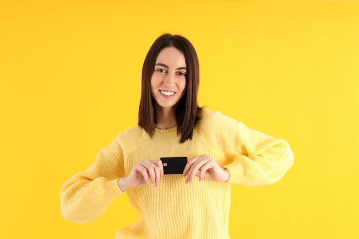 Foto jovem garota atraente com cartão em fundo amarelo