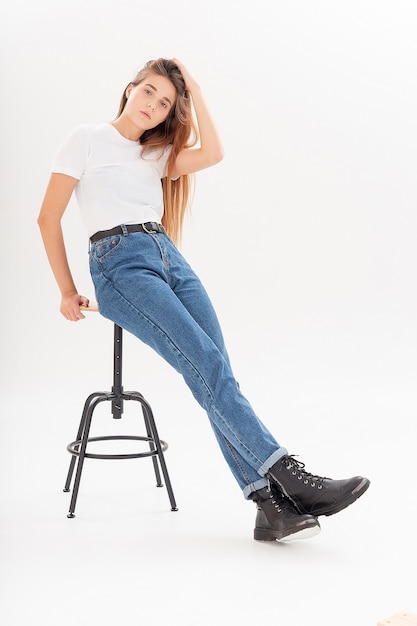 Jovem garota bonita caucasiana com cabelo comprido em camiseta, jeans azul no estúdio