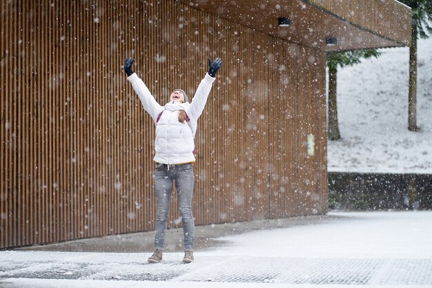Jovem garota caucasiana rindo pegando flocos de neve em seu toungue