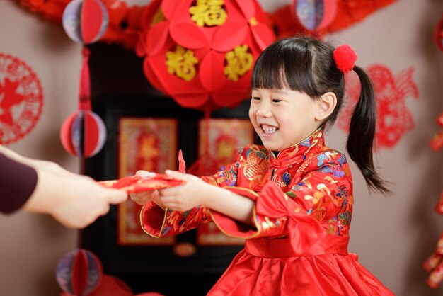 Jovem garota chinesa vestida tradicionalmente com envelope vermelho