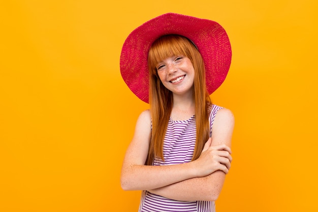 Jovem garota com cabelo vermelho e chapéu rosa sorri e espera algo isolado em amarelo