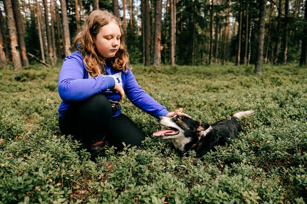 Jovem garota com cachorro posando na floresta