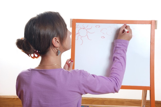 Foto jovem garota desenhando no tabuleiro branco