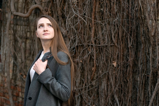 Jovem garota em um terno formal em fundo de cerca de madeira velha. Retrato de mulher de negócios.