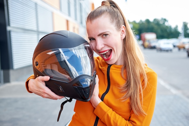 Jovem garota engraçada atraente com lábios pintados vermelhos, posando com capacete preto.