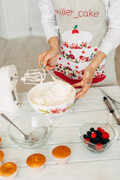 Jovem garota fazendo creme para cupcakes.