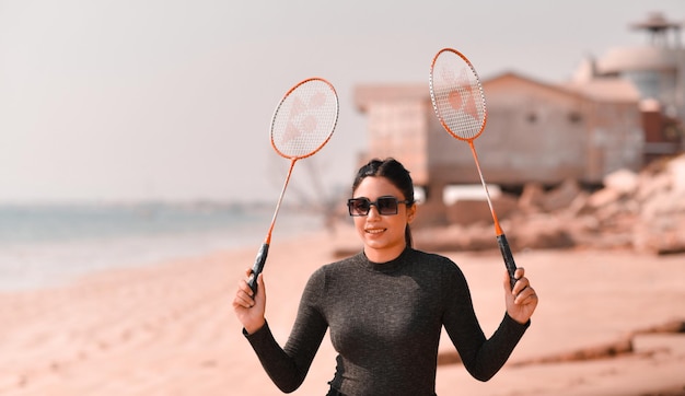 jovem garota feliz jogando tênis na praia modelo paquistanês indiano