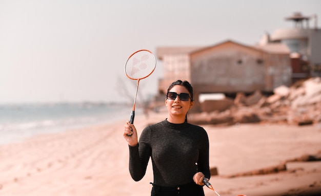 jovem garota feliz jogando tênis na praia modelo paquistanês indiano