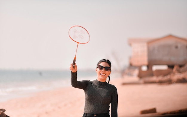 Foto jovem garota feliz jogando tênis na praia modelo paquistanês indiano