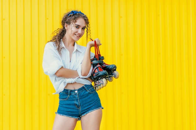 Jovem garota feliz segurando rolos na parede amarela