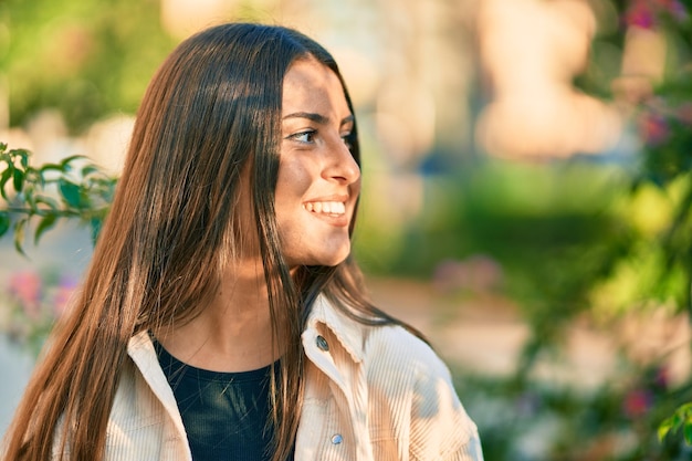 Jovem garota hispânica sorrindo feliz em pé no parque