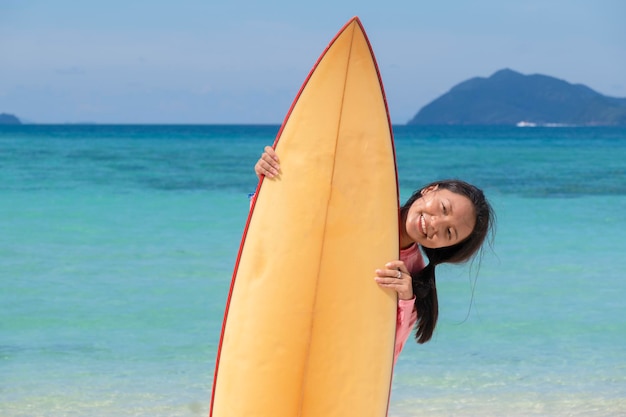 Jovem garota jogando surf na bela vista da paisagem do mar.