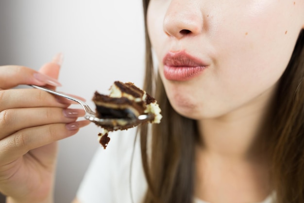 Jovem garota linda comendo bolo em close-up foto de colheita boca de mulher comendo um pedaço de bolo