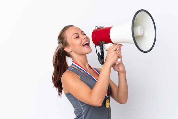 Jovem garota russa do esporte com medalhas isoladas no fundo branco gritando através de um megafone