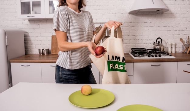 Jovem garota segurando um saco de pano. Na cozinha Eu não sou de plástico