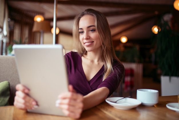 Jovem garota usando 4g em tablet no café.