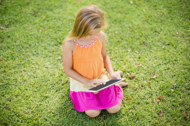 Jovem garota usando tablet digital no parque