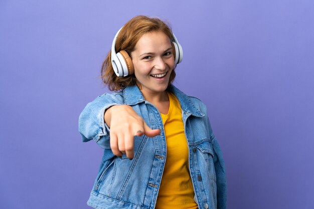 Jovem georgiana isolada na parede roxa ouvindo música