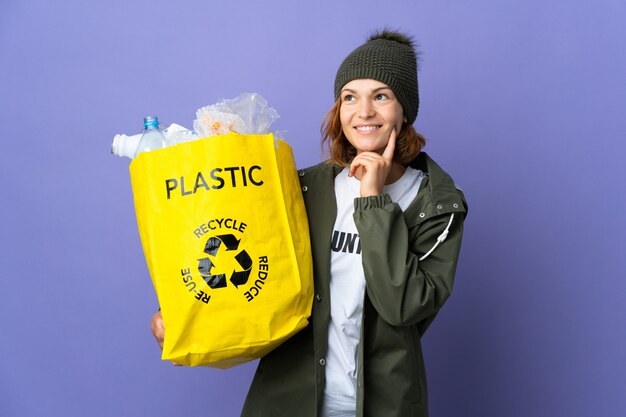 Jovem georgiana segurando uma sacola cheia de garrafas plásticas para reciclar pensando em uma ideia enquanto olha para cima