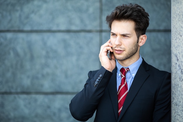 Jovem gerente ao telefone ao ar livre em um ambiente urbano