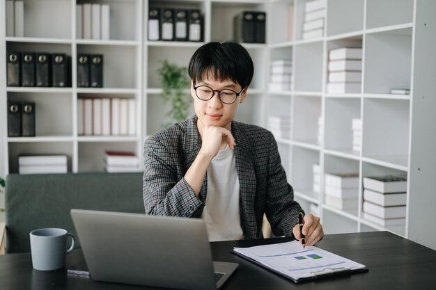 Jovem gerente executivo de negócios olhando para o laptop assistindo a treinamento on-line de webinar ou tendo reunião virtual de videoconferência fazendo pesquisa de mercado trabalhando em escritório moderno