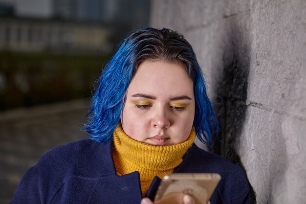 Jovem gordinha lê mensagens na tela do telefone na noite fria de outono ao entardecer.