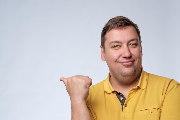 Jovem gordo fazendo um gesto apontando de lado isolado no fundo branco