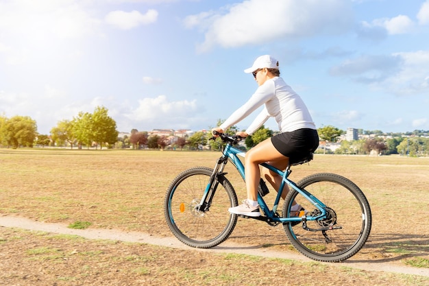Jovem gosta de um dia ensolarado se exercitando com sua bicicleta no parque da cidade