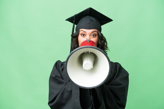 Jovem graduada universitária argentina gritando através de um megafone em um fundo isolado