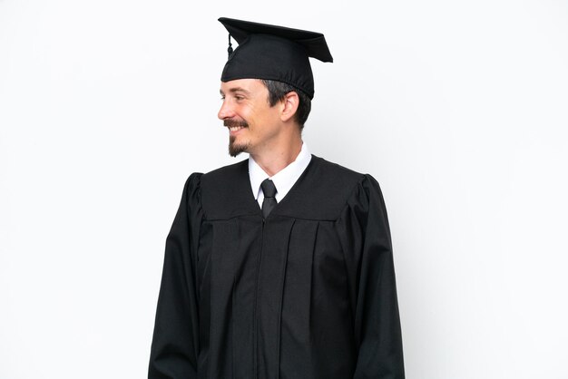 Foto jovem graduado universitário isolado em fundo branco olhando para o lado