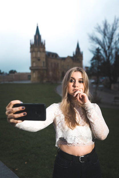Jovem gravando a si mesma com um celular na rua.