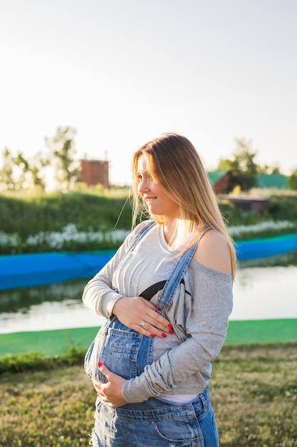 Foto jovem grávida abraçando a barriga ao ar livre