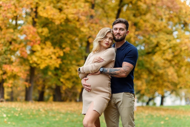 Jovem grávida e seu belo marido estão andando no parque outono