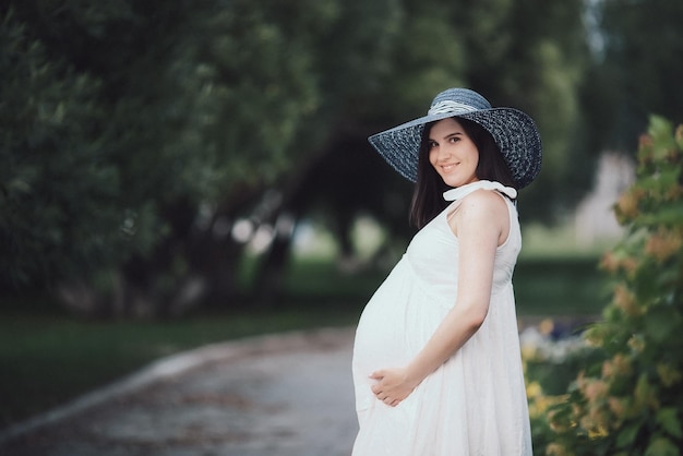 Jovem grávida em um dia de verão no parque Mãe esperando o nascimento do bebê