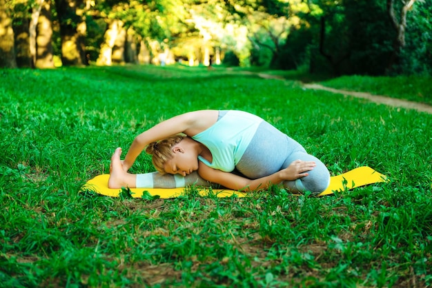 Jovem grávida fazendo ioga no parque