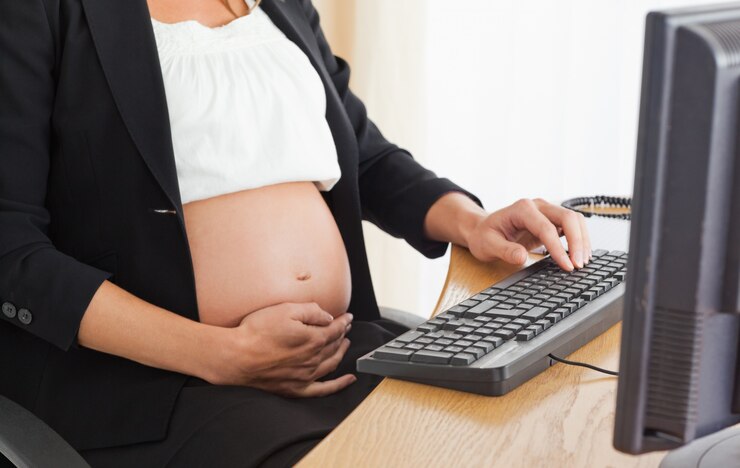 Foto jovem grávida no telefone trabalhando com um computador