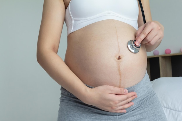 Jovem grávida segura estetoscópio e ouve seu bebê