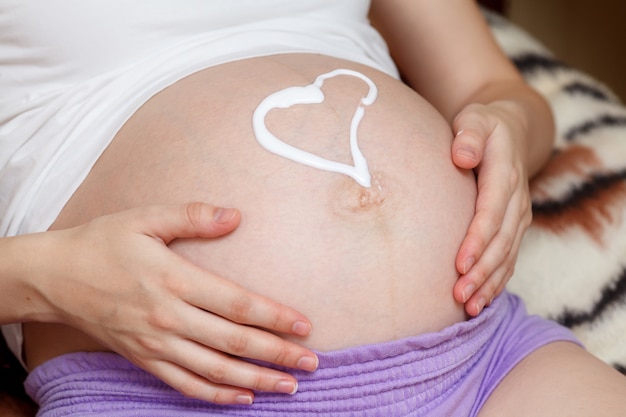 Jovem grávida segurando e tocando a barriga