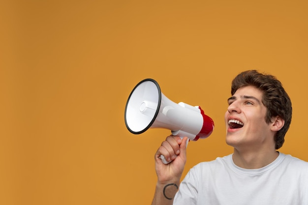 Jovem gritando em megafone fazendo anúncio contra fundo amarelo