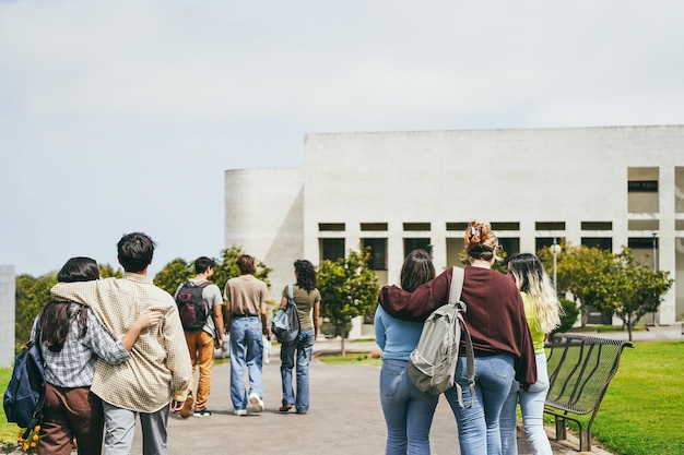 Jovem grupo de amigos se divertindo lá fora com o prédio da escola em segundo plano