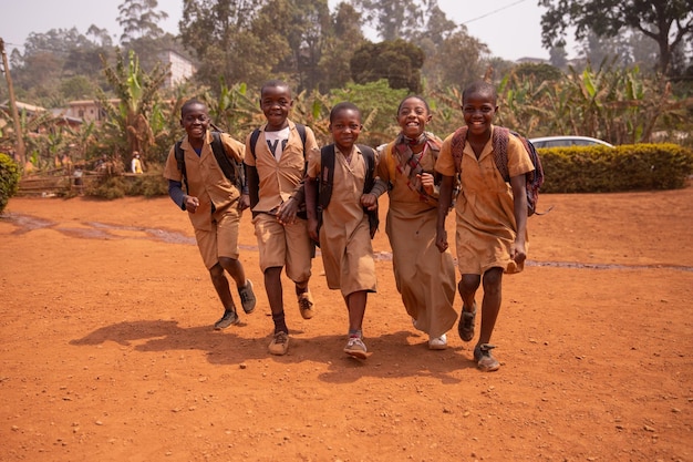 Jovem grupo de crianças africanas todos juntos no pátio da escola se divertindo jogando de mãos dadas