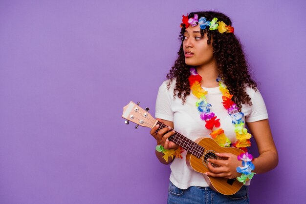 Jovem havaiana tocando cavaquinho isolada em roxo