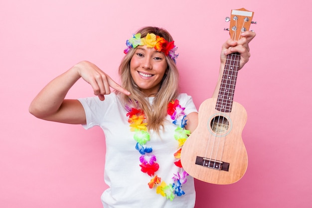 Jovem havaiana tocando um ukulele isolado em um fundo rosa