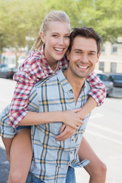 Jovem hip homem dando a namorada loira um piggy back