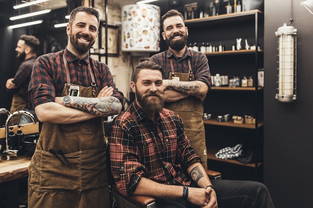 Jovem hippie bonito visitando o cabeleireiro e barbeiro na barbearia.