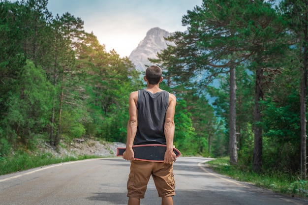 Jovem hippie segurando um longboard legal na mão