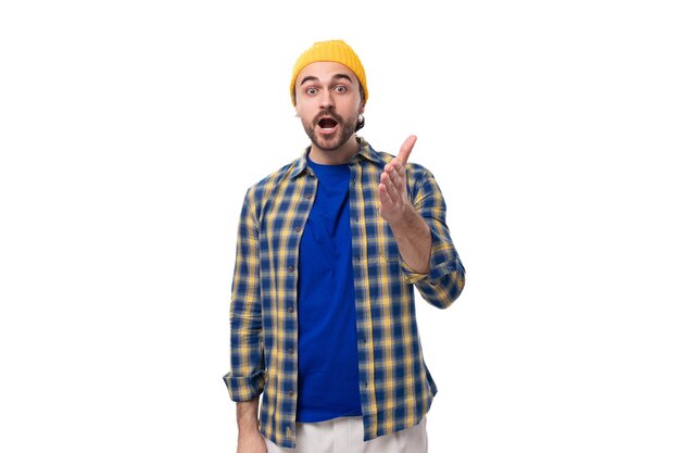 Jovem hipster lindo e surpreendido com boné amarelo e camisa em fundo branco com espaço de cópia