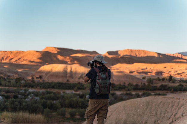 Foto jovem hipster tirando fotos com sua câmera no deserto